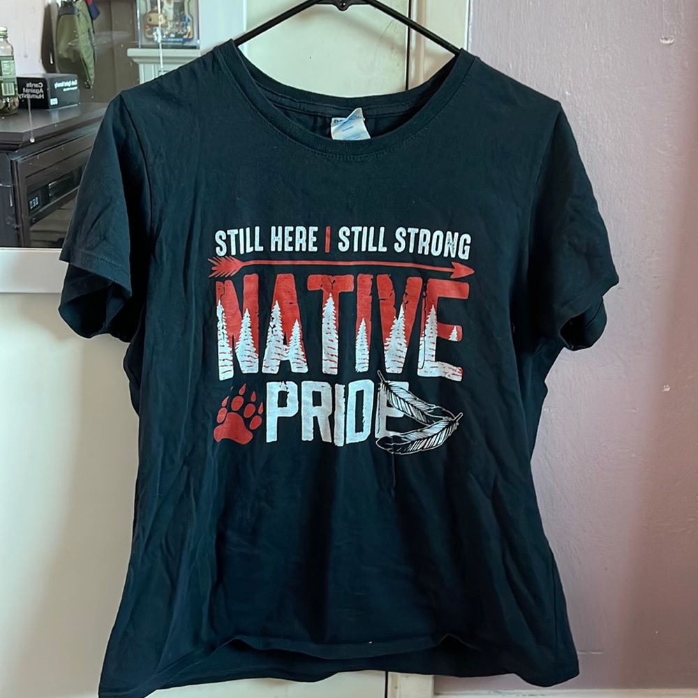 Native American shirt, it says “STILL HERE, STILL STRONG, NATIVE PRIDE”